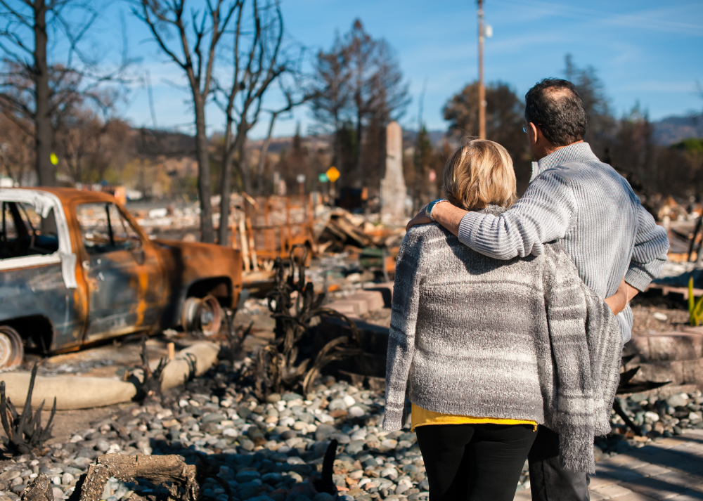 couple looks at house and yard destroyed after a wildfire